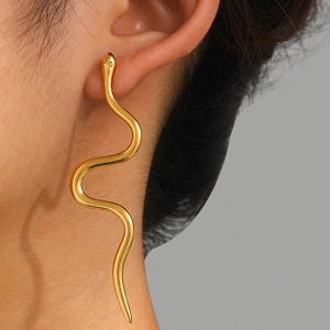 Close-up of golden wavy snake earrings with a high-polished finish on female model