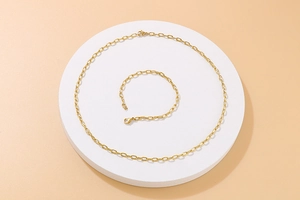 Flat lay of gold tone hammered chunky chain necklace and bracelet set on a white stand