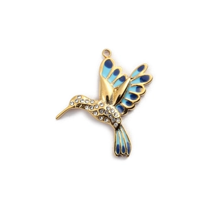 Dettaglio di un ciondolo a colibrì in oro e smalto blu con cristalli bianchi brillanti