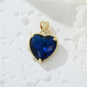Macro di un ciondolo a cuore in oro 14K con zircone blu scuro su pietra bianca
