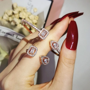 Rose gold jewelry set with bangles and zircon rings worn on a model hand with red nails