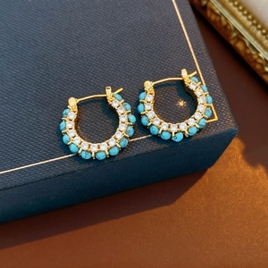 Close-up of 18k gold plated hoop earrings with blue beads and cubic zirconia detail