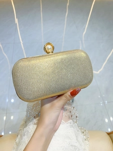 Dettaglio della pochette da sera dorata glitterata con chiusura a perla e telaio in metallo
