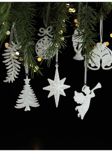 Close-up of glittery white Christmas tree and star ornaments on festive pine branches