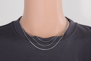 Close-up of triple-layered silver snake bone chain necklace in polished stainless steel