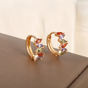 Gold circular hoop earrings with colorful marquise zircons on brown leather texture