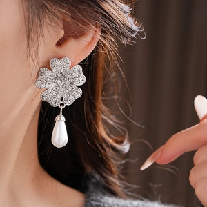 Close-up of silver floral earrings with crystal pavé and white drop pearl pendant