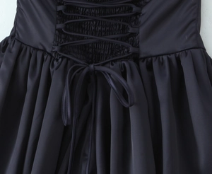 Détail d'une robe noire dos nu avec tissu smocké et nœud papillon à lacets à l'arrière