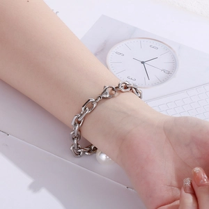 Close-up of a silver chunky chain bracelet with a large white pearl on a woman's wrist
