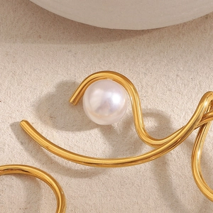 Macro shot of 18K gold plated knotted metal earrings with a lustrous faux pearl accent