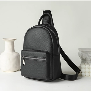 Close-up of black lychee texture PU leather with silver metal zipper on a mini chest bag