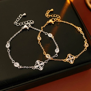 Macro shot of gold and silver flower bracelets with oval zircon stones on black leather
