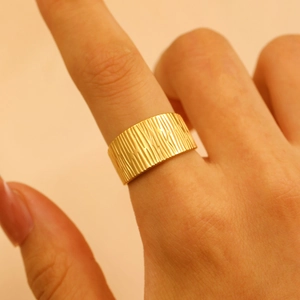Detailed close-up of a wide gold stainless steel ring with a unique bark-like texture finish
