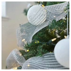 Close-up of white mesh ribbon and glitter ornaments on a Christmas tree with warm lights