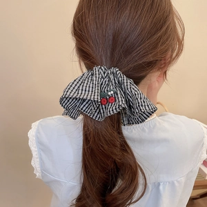 Détail d'un chouchou en tissu à carreaux avec broderie cerise et perles sur queue