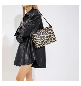 Dettaglio ravvicinato della borsa tote leopardata con tracolla sottile su giacca nera