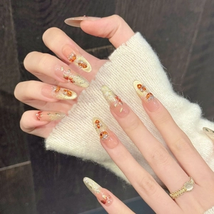 Gouden glitter plaknagels in lange amandelvorm met amberkleurige stenen en strassteentjes
