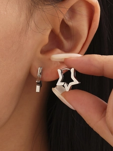 Close-up of minimalist star-shaped stainless steel hoop earring worn on the earlobe