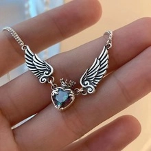 Detalle del colgante alas de ángel de plata con corazón irisado y adorno de corona