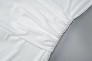 Detail of white sleeveless dress showing soft elastic fabric texture and neat stitching