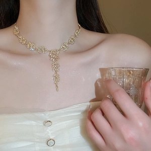 Détail d'un collier feuille doré élégant avec strass brillants et long pompon sur modèle