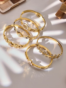 Close-up of luxury gold-plated bangle set featuring tree of life and clover motifs