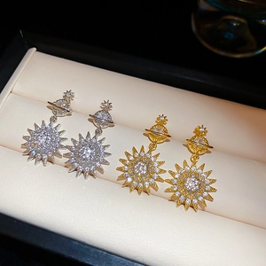 Macro shot of silver and gold Saturn earrings with sparkling cubic zirconia in a jewelry box