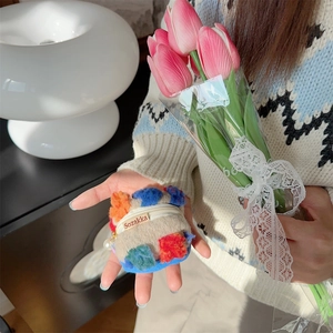 Primo piano di una mini pochette in peluche per rossetto e auricolari tenuta in mano