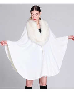 White knitted poncho with fluffy faux fox fur collar on an elegant model detail
