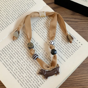 Detail of knitted cherry pendant necklace with dachshund charm on vintage book