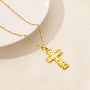 Detail of gold cross pendant with lava texture on white ceramic tray background