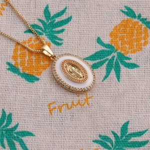 Detailed close-up of a gold-plated medallion pendant with white enamel and tiny zircons