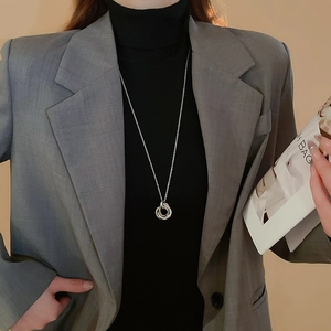 Close-up of interlocking silver rings pendant necklace on a model wearing a grey blazer