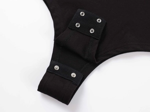 Detail view of silver metal snap button closure on black ribbed cotton bodysuit