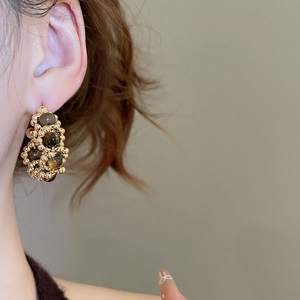 Close-up of vintage tiger eye bead and gold sphere woven earring worn on model