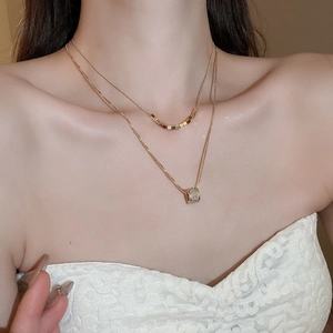 Detail of 18k gold-plated double-layer necklace with a micro-pave cylinder pendant charm