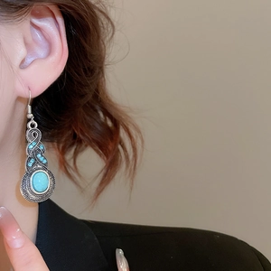 Close-up of vintage leaf tassel earrings with oval turquoise on a fashion model