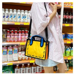 Detailed view of the 2D cartoon style yellow canvas tote bag worn by a model in a supermarket