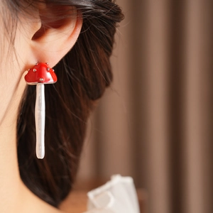 Close-up of vintage mushroom pearl earring in red enamel with white dots on model