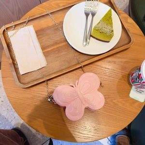 Mini sac papillon rose en gelée avec bandoulière chaîne dorée sur une table