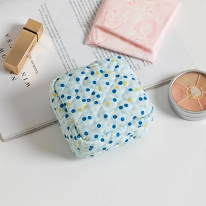 Quilted floral sanitary napkin storage bag with blue polka dots and travel accessories