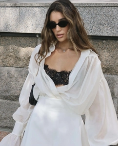 Detailed texture of a white sheer chiffon long sleeve shirt with black lace bralette top