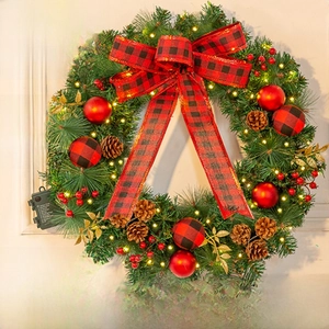 Close-up of snowy Christmas wreath with LED lights, pine cones, and red plaid bow