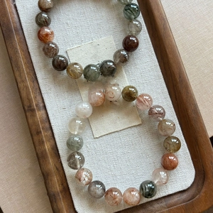 Macro shot of natural rutilated quartz beaded bracelets on a rustic wooden and linen tray