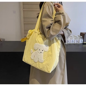 Detail of yellow canvas tote bag with poodle patch and drawstring closure on shoulder