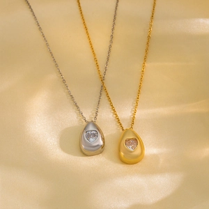Water drop zircon necklace in gold and silver finish with heart stone on silk background