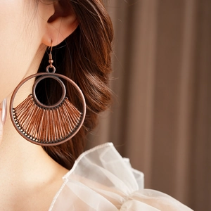 Detailed view of bohemian vintage round hollow earrings with brown woven cord texture