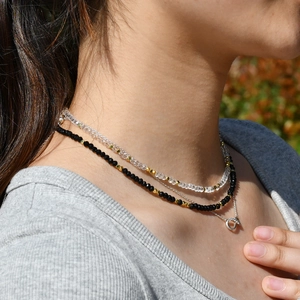 Close-up of triple layered necklace with crystal beads and a simple circular pendant