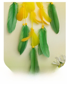 Detail of vibrant green and yellow feathers with decorative beads on a sunflower dreamcatcher