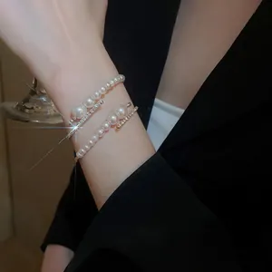 Elegant multi-layer pearl open bracelet with sparkling diamonds and gold metal finish